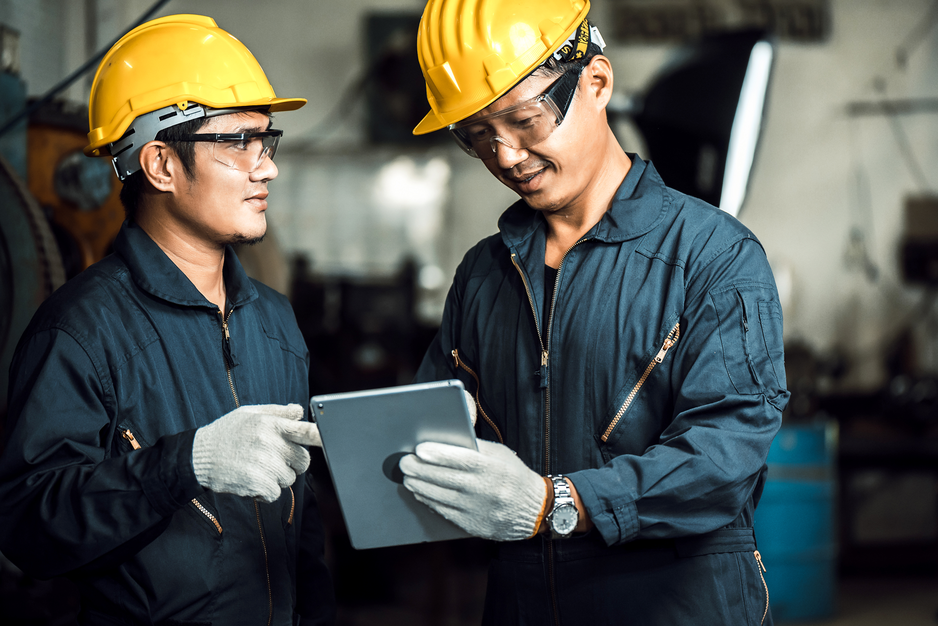Two male workers in PPE looking at training content on a tablet.
