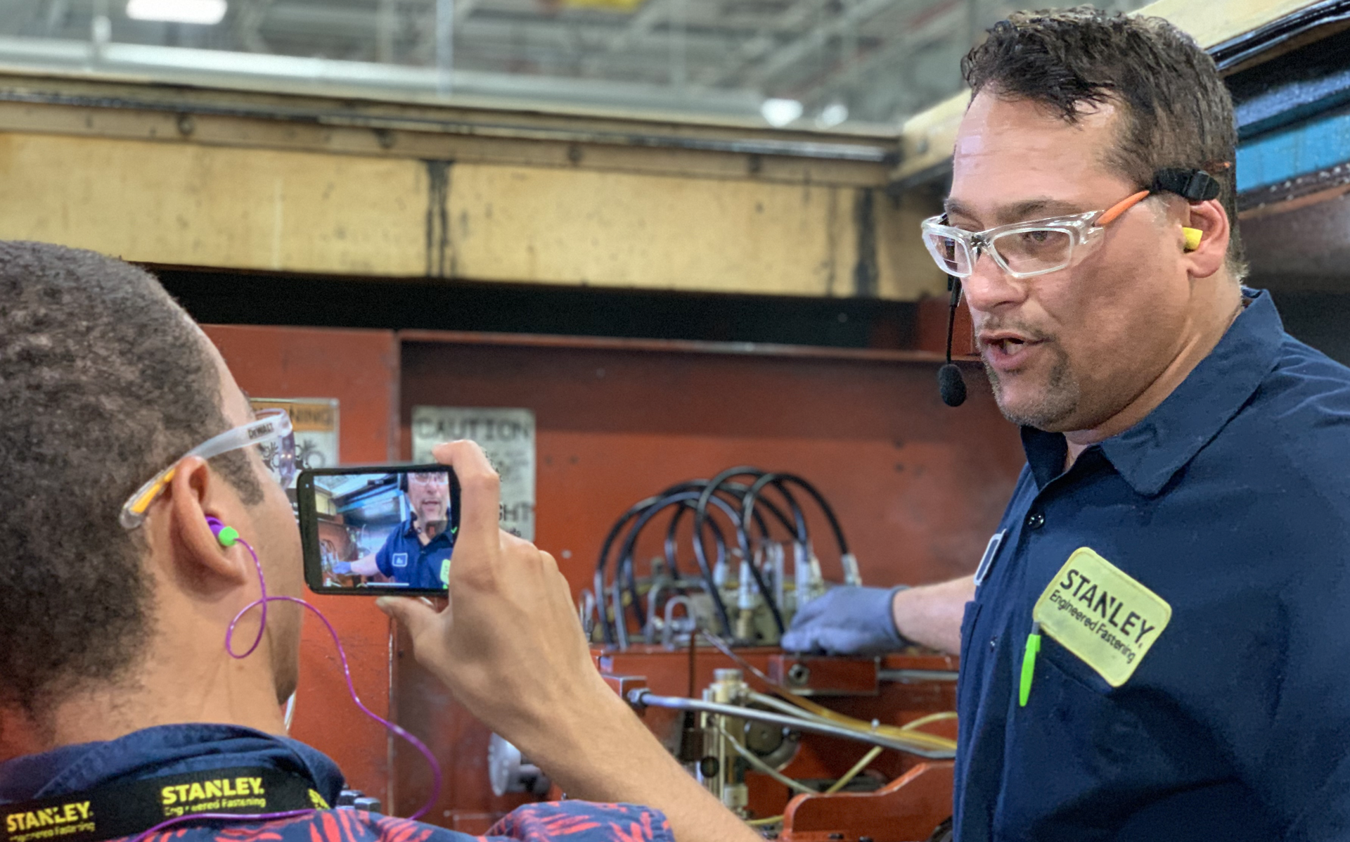 A Stanley Black & Decker employee using DeepHow on his phone to film another employee.