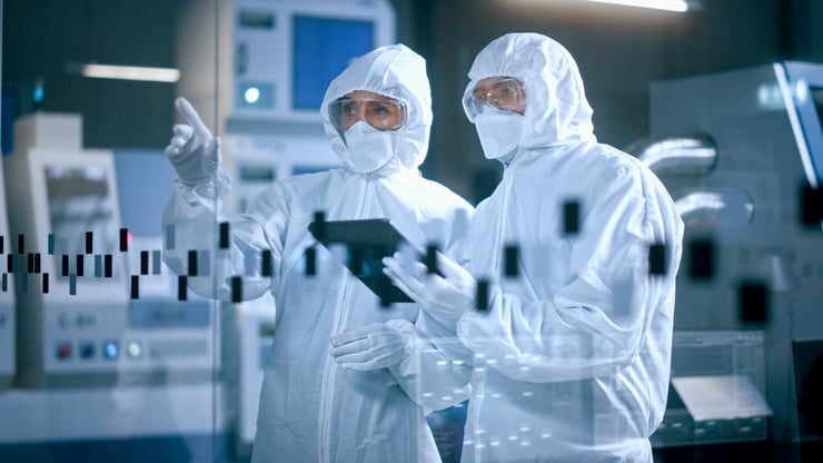 Stock image of two workers hazmats suits standing together holding a mobile tablet
